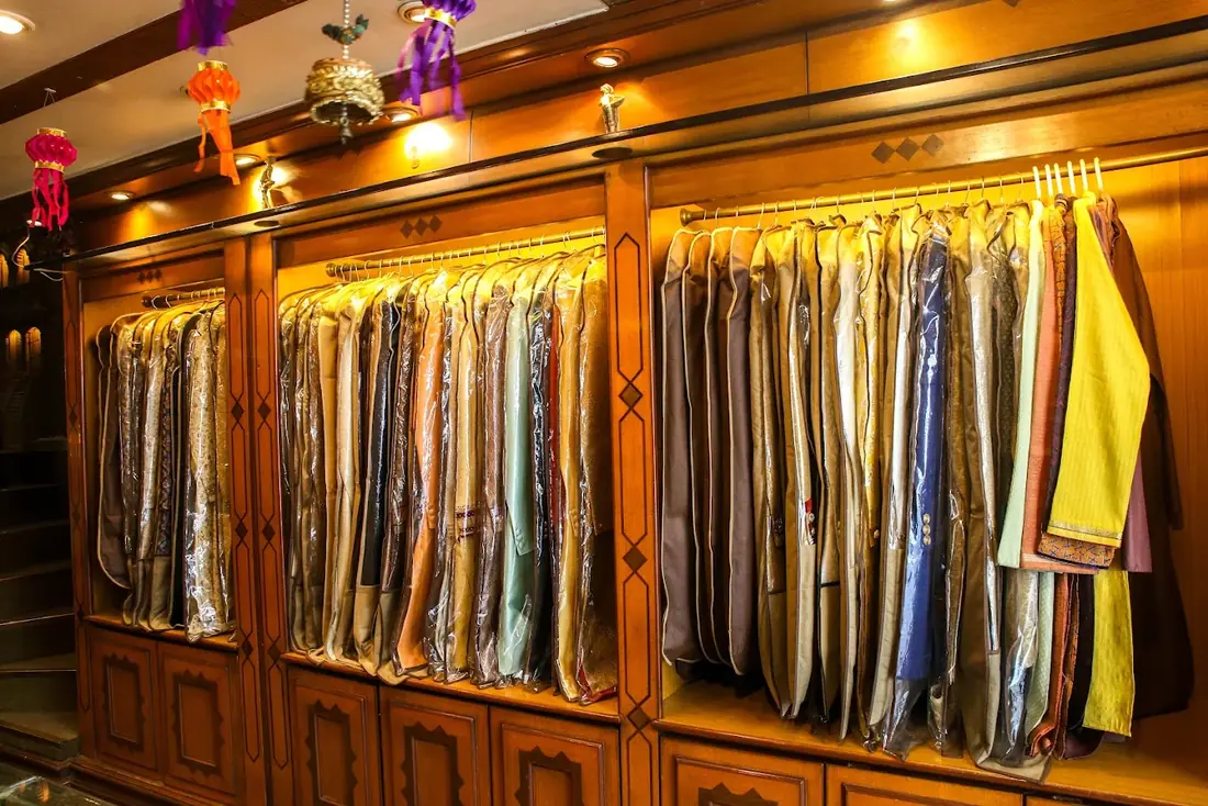 Teak cabinets with sherwanis and jackets hanging in covers